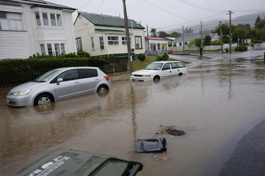Stormwater halfway up the wheels of cars parked on a flooded Auckland street after heavy rain