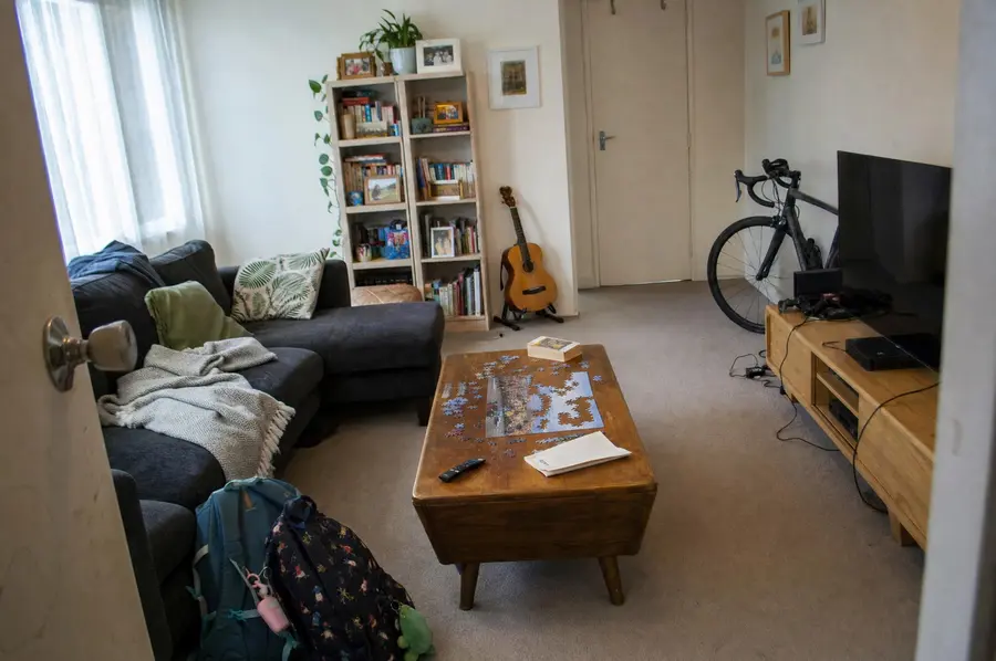 Lounge of a New Zealand home with a sofa, television, bookshelf and lamp on a winter evening