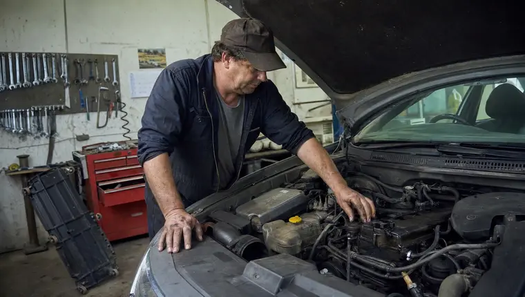 Mechanic inspecting an engine bay, illustrating the mechanical breakdown that comprehensive cover excludes