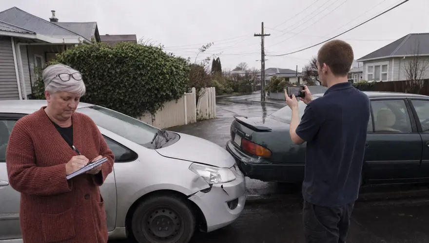 Two drivers calmly exchanging details between lightly damaged cars after a minor collision